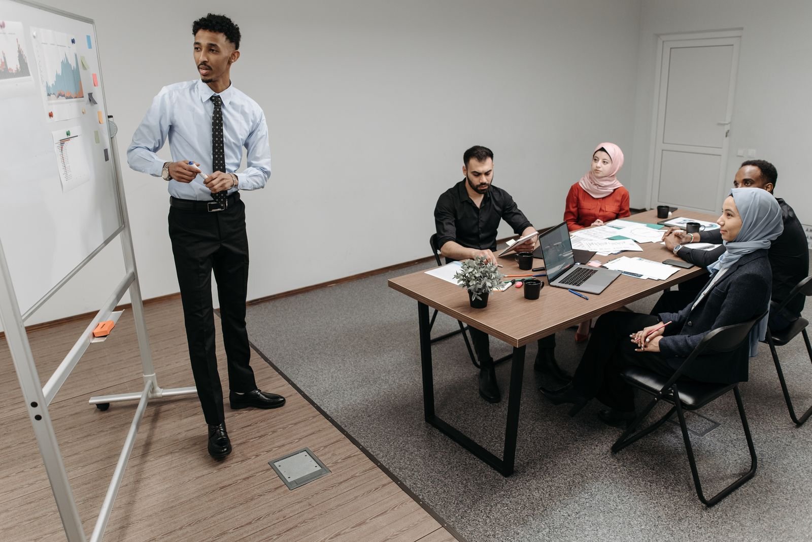 Man presenting graphs to colleagues on a whiteboard